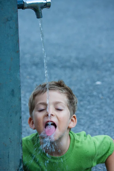 Close-up de bebê bebendo fonte com salpicos de água — Fotografia de Stock