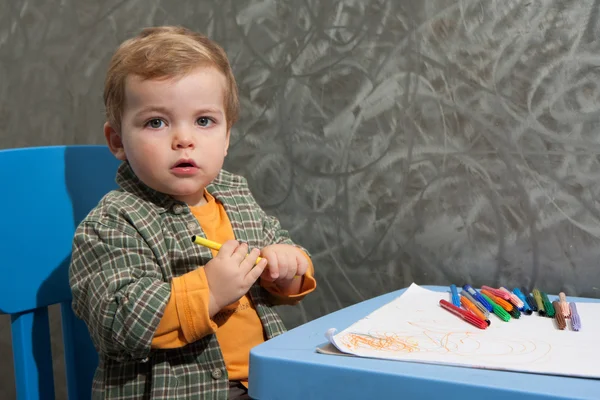 Child sitting at a table drawing with colored markers — Stock Photo, Image