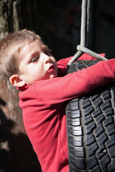 Bambino su altalena realizzato con pneumatico auto — Foto Stock