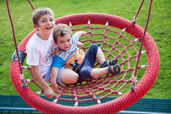 Two children fun on swing round — Stok fotoğraf