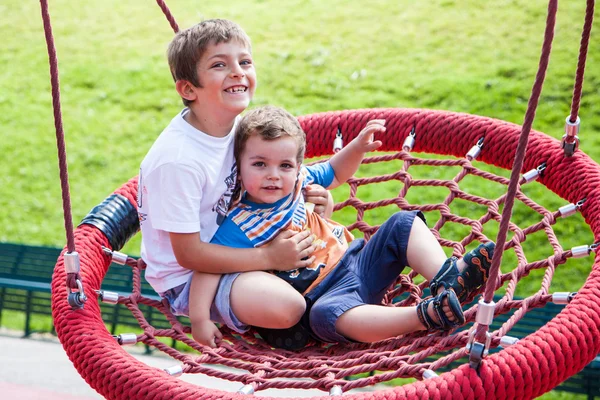 Two children fun on swing round — Stok fotoğraf