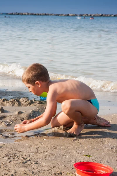 Menino brincando com areia no mar itália praia — Fotografia de Stock