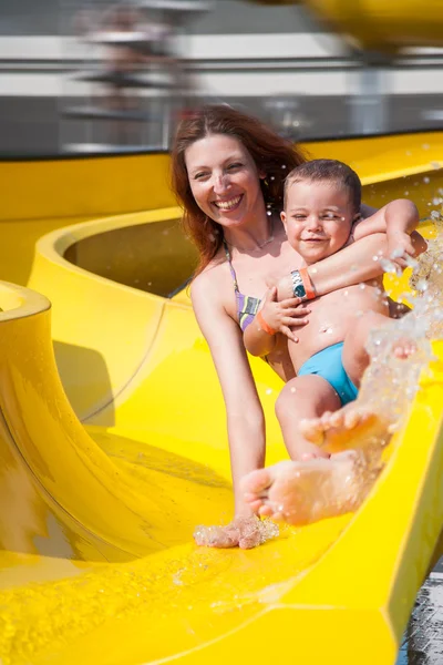 Kind und Mutter spielen mit der Rutsche im Pool — Stockfoto