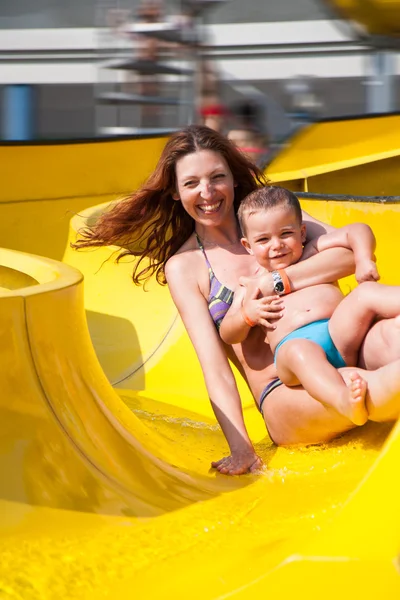 Criança e mãe brincando com o slide na piscina — Fotografia de Stock