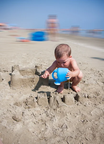 Pequeño niño jugando con la arena y la regadera en la playa italia mar — Foto de Stock
