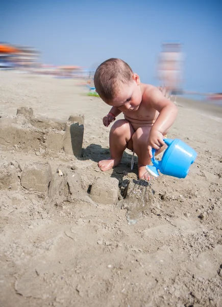 Menino brincando com areia e regando lata no mar itália praia — Fotografia de Stock