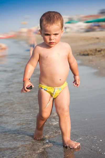 Bebê feliz brincando na água na praia — Fotografia de Stock