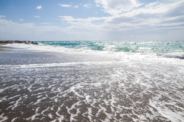 A hullámok feltörése a kihalt strand, a háttér kék sk — Stock Fotó