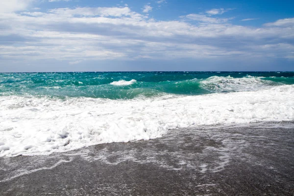 Die Wellen brechen am einsamen Strand, der Hintergrund blau sk — Stockfoto