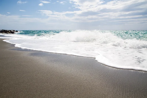 A hullámok feltörése a kihalt strand, a háttér kék sk — Stock Fotó