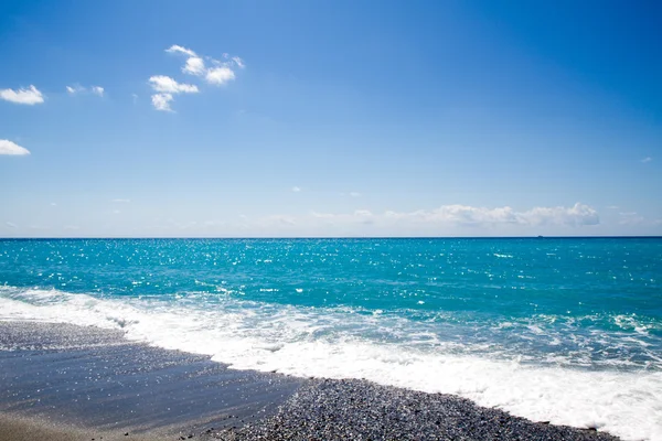 De golven breken op het verlaten strand, de achtergrond blauw sk — Stockfoto