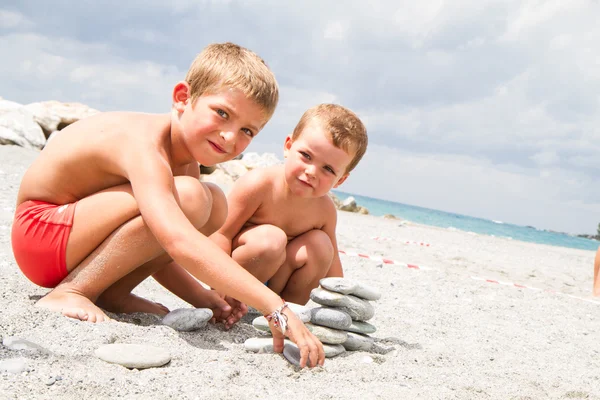 Irmãos pequenos felizes brincando na praia — Fotografia de Stock