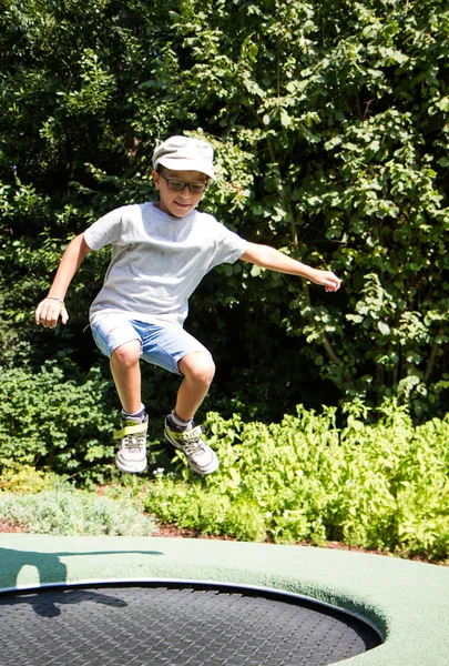 Dítě s brýlemi, skákání na trampolíně — Stock fotografie