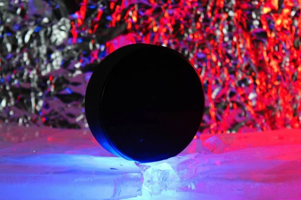 Hockey puck stands on the edge in cracked ice. A red-blue light falls on him. Czech hockey concept. The hockey puck broke the ice. Long live the World Hockey Championship.