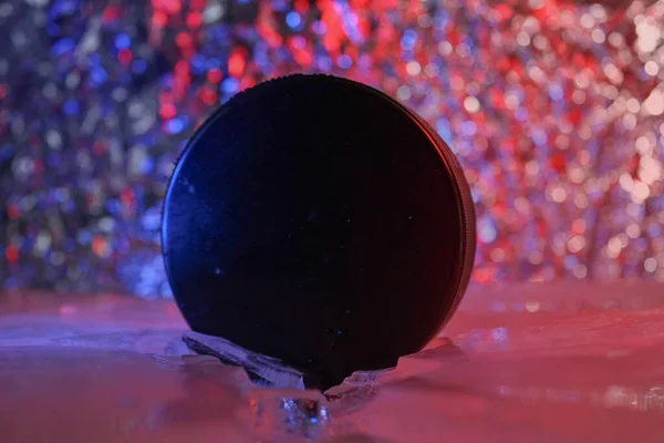 Hockey puck stands on the edge in cracked ice. A red-blue light falls on him. Czech hockey concept. The hockey puck broke the ice. Long live the World Hockey Championship.