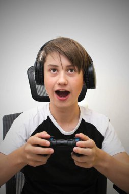 Çocuk bir bilgisayar oyunu oynuyor ve bir oyun sandalyesinde oturuyor. Kazanacağı için heyecanlı..