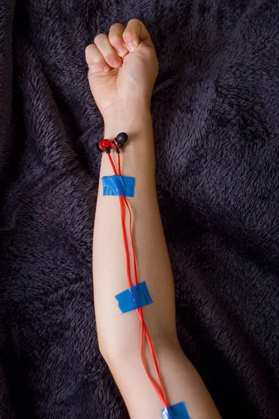 Headphones with cord stuck with blue adhesive tape to the arm. Technology moves the world. One cannot do without them.