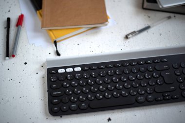 Çalışma alanı. Siyah klavye, günlükler ve arka planda birkaç kalem. Düz yatıyordu.