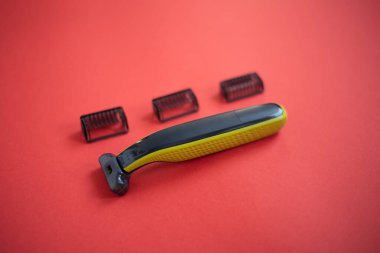 Kırmızı arkaplanda üç eklentisi olan sakal kesicisi. 