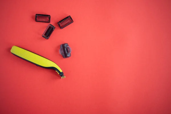 Beard trimmer with three attachments on the red background.