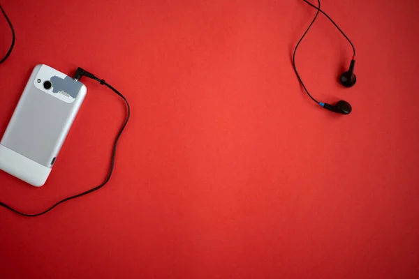 Alte Veraltete Und Verschlissene Mobiltelefone Und Kabelgebundene Ohrhörer Auf Rotem — Stockfoto