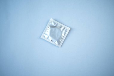 Mavi arka planda prezervatif. Güvenli seks kavramı.