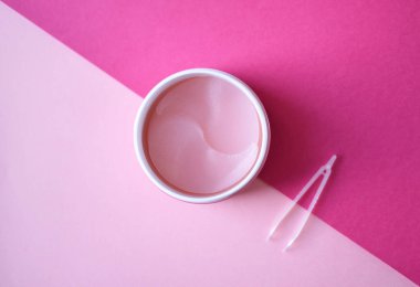 Pastel arka planda cilt bakımı için hidrojel kozmetik göz bandı. Yüz gerdirme, yaşlanma önleyici kırışıklık önleyici ürünler. Beyaz bir kapta göz altı yamaları, yaşlanma önleyici cilt bakımı. Kopya alanı.