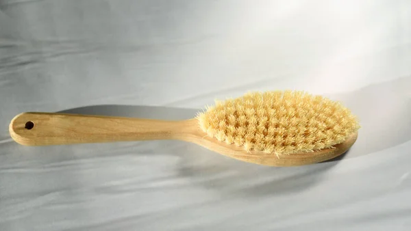 Massage brush for the body. Dry lymphatic drainage massage. Wooden brush made of cactus and boar fiber. On a light background with starfish. Bathroom treatments. Homemade body care.