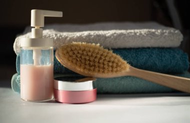 Banyo tesisleri ve banyoda bir yığın temiz havlu. Kuru masaj için ahşap fırça, sıvı sabun ve vücut kremi.