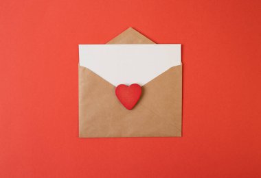 İçinde beyaz notlar olan bir zarf ve kırmızı arka planda sevgililer günü kalpleri. Düz yerde, üst tarafta. Sevgililer Günü konsepti için romantik aşk mektubu.