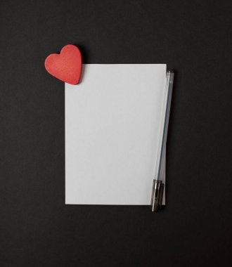 Koyu renkli arka planda kırmızı kalpli bir kağıt parçası. Sevgililer Günü konsepti için romantik aşk mektubu. Metin için boşluk.