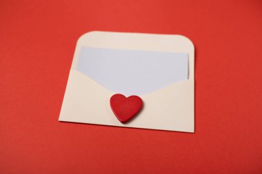 Kırmızı arka planda kırmızı ahşap bir kalp olan bir zarf. Düz konum, üst görünüm, metin için boşluk. Sevgililer Günü konsepti için romantik aşk mektubu.