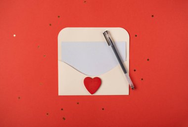 Kırmızı arka planda kırmızı ahşap bir kalp olan bir zarf. Düz konum, üst görünüm, metin için boşluk. Sevgililer Günü konsepti için romantik aşk mektubu.