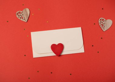 Kırmızı arka planda zarf ve kırmızı kalp. Düz yatıyordu. Sevgililer Günü konsepti için romantik aşk mektubu.