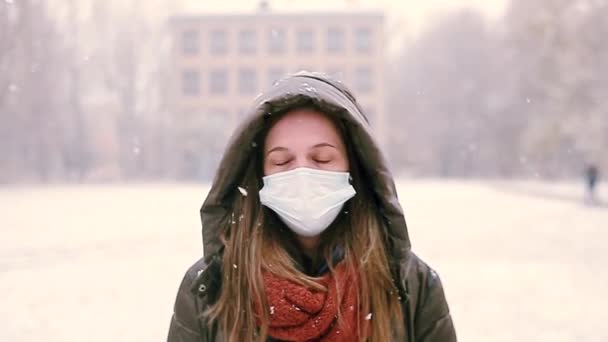 The girl takes off the medical mask and enjoys the first snow — Stock Video