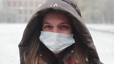 Maskeli bir kız ilk kar yağdığında sevinir ve selfie çeker.