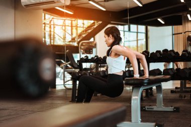 Güzel genç Asyalı kadın spor salonunda şınav çekiyor.