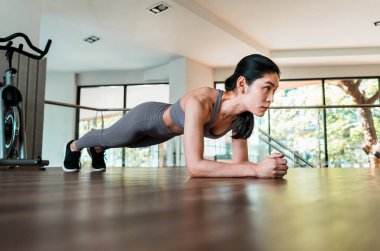 Slim fitness genç kadınlar spor salonunda planking egzersizi yapıyor.