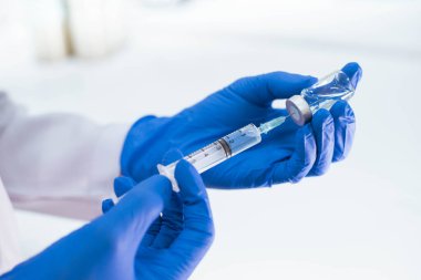 Mavi eldivenli doktor şırıngayı aşıyla dolduruyor.