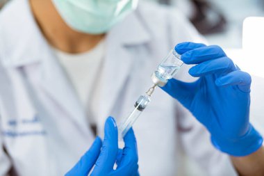 Mavi eldivenli doktor şırıngayı aşıyla dolduruyor.