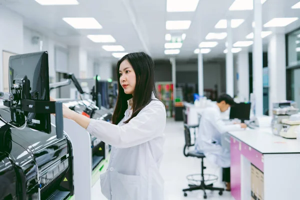 young female scientist working with automation blood analyzer in medical laboratory