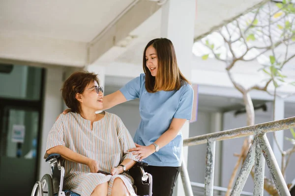 Smilende Fysioterapeut Tager Sig Den Glade Senior Patient Kørestol - Stock-foto
