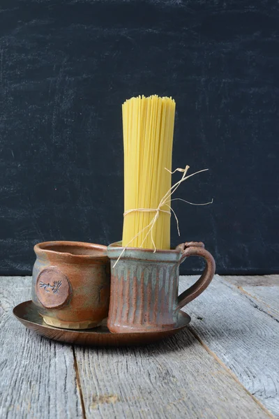 Spaghetti cru dans l'usure de la terre sur fond de bois rustique — Photo