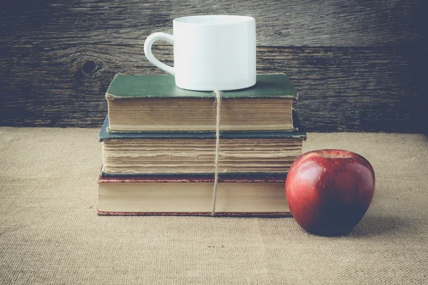 Bücher und Apfel mit Kaffeetasse auf Retro-Hintergrund mit Hirsch — Stockfoto