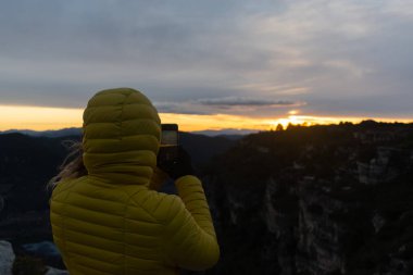 Kadın gün batımının fotoğrafını çekiyor.
