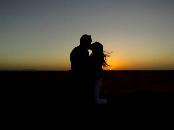 Çölde öpüşen bir çiftin silüeti.