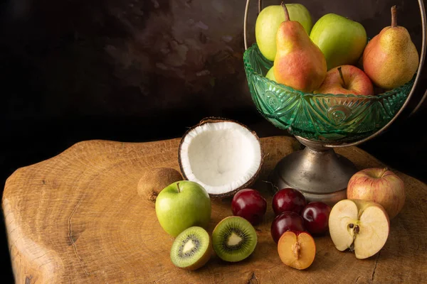 Arrangement of fruits in an old fruit bowl on rustic wood with spotted background, selective focus.