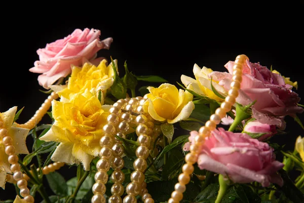 Bouquet of roses with dew with pearl necklaces on black background, selective focus.