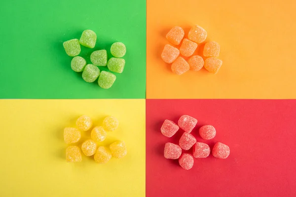 Gummy candy, arrangement of color-separated gummy candy placed on a colored surface.
