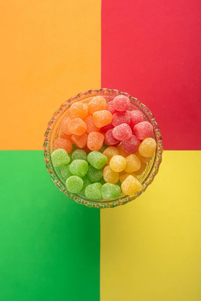 Gummy candy, arrangement of gummy candy seen from above in a glass jar on a colored surface.